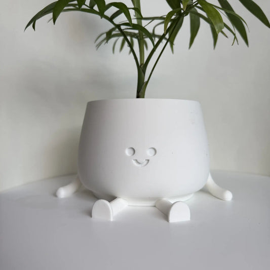 Kolorowa doniczka na kwiaty drukowana w technologii 3D z oczami i uśmiechniętą buzią.