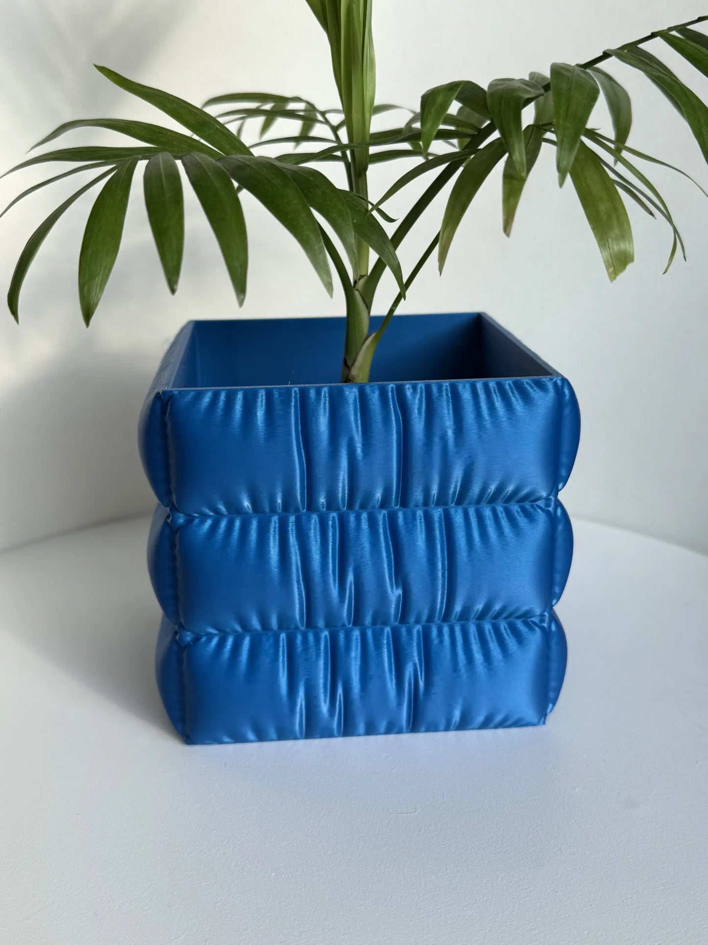 Doniczka do roślin do użytku wewnętrznego z wykończeniem o fakturze tkaniny.