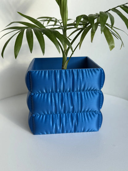 Doniczka do roślin do użytku wewnętrznego z wykończeniem o fakturze tkaniny.