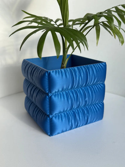 Doniczka do roślin do użytku wewnętrznego z wykończeniem o fakturze tkaniny.